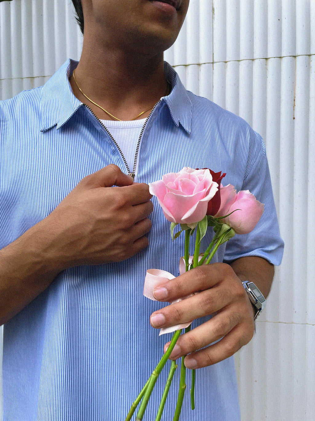 Creatively directed image of an individual wearing the Zerodays Pinstripe shirt with the half zipper open. The individual has a small bunch of pink and red roses in his hand.
