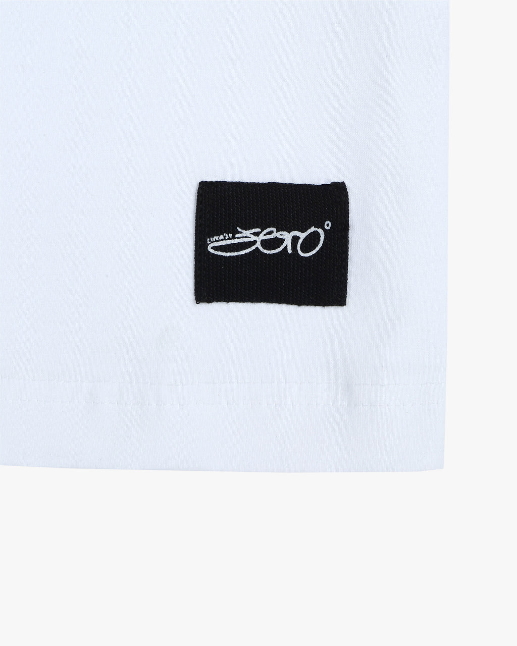 A closeup of the distinctive Zerodays signature tag located at the bottom of the 'Phoenix White Tee' from Collection Zero, highlighting the premium quality fabric used in its production.