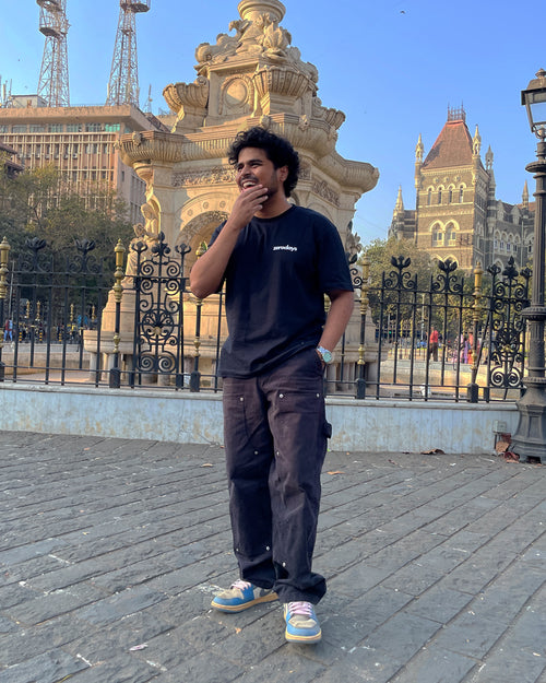 Featuring a stylised image of the black Zerodays t-shirt styled and worn by the co-founder of Zerodays against an aesthetic city style and architecture heavy background. 