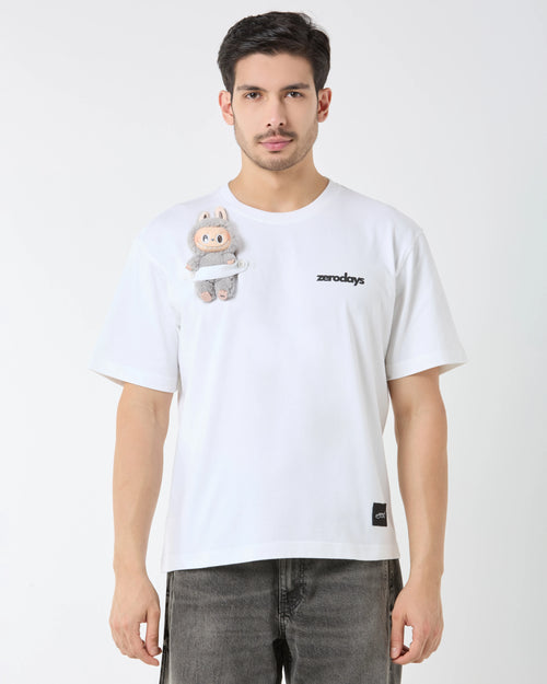 Man wearing a white t-shirt with a small plush toy attached, on a plain background
