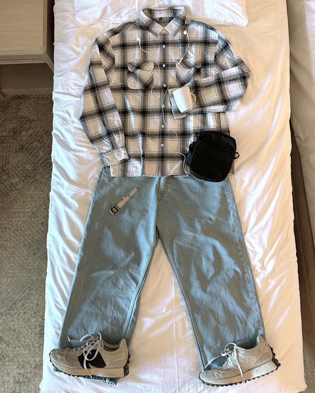 A stylised creative of the Zerodays white flannel with accessories and shoes laid out on a bed. 