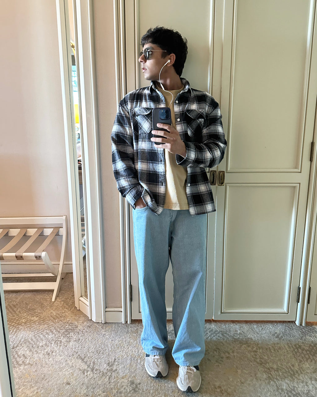 A mirror selfie of a guy styling the Zerodays Black essential flannel wearing wired white earphones.